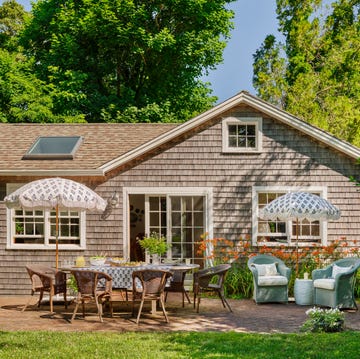 patio outside a cedar shake cottage with a dining table, chairs, and umbrellas