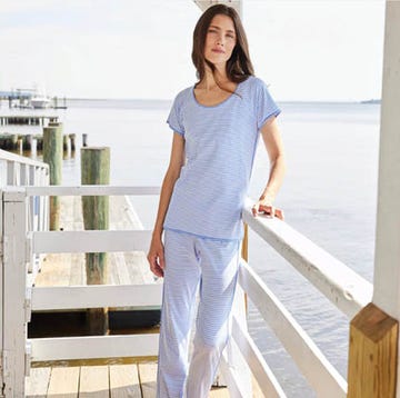 a stack of gold and pearl bracelets next to a woman in blue and white pajamas on a dock